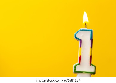 Number 1 birthday celebration candle against a bright yellow background