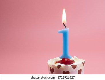 Number 1 Burning birthday celebration candles in a cupcake isolated on pastel pink background, Front view Blank for design copy space.
