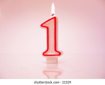 A Number 1 Candle Lit Against Pink Background.