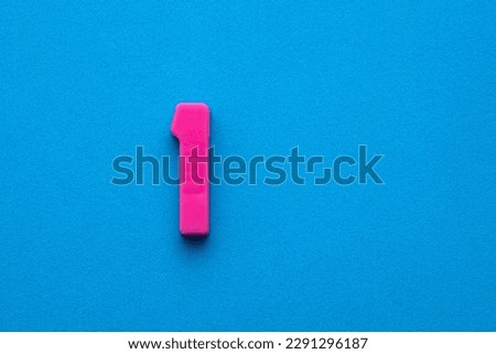 Number 1 color pink - Plastic piece on blue foamy background