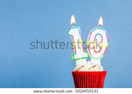 Number 10 birthday candle in a cupcake against a blue background