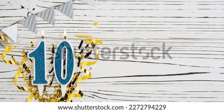 Number 10 blue celebration candle on white wooden background. Happy birthday candles. Concept of celebrating birthday, anniversary, important date, holiday. Copy space. Banner