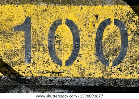 The number 100, one hundred, one zero zero; painted in black and yellow; an abstract background for graphic design  a symbol of birthdays, dates, anniversaries, markers and milestones.