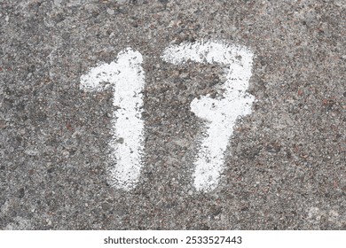 Number 17 painted on concrete. Numbered parking spot. Marked on ground with white paint. Parking lot numers background. - Powered by Shutterstock