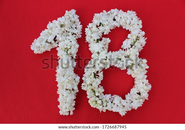 赤い背景に18の番号が白いライラック花で書かれている 18番は赤い背景に生花で書かれている 花が並んだアラビア数字 の写真素材 今すぐ編集