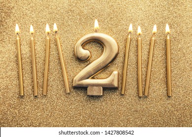 Number 2 gold celebration candle on a glitter background