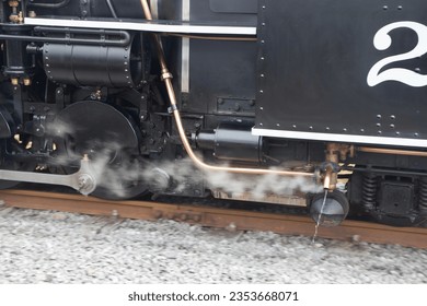 The number 2 steam engine on the Brecon mountain railway. Taken on a bright but slightly cloudy summers day. This shows the steam and water from the boiler in action, as well as the clear number 2.