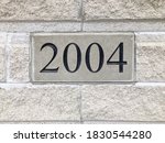 Number 2004 plate on grey brick wall.