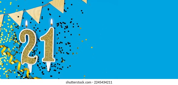 Number 21 gold celebration candle on star and glitter blue background. Copy space. Banner - Powered by Shutterstock