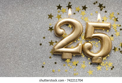 Number 25 gold celebration candle on star and glitter background