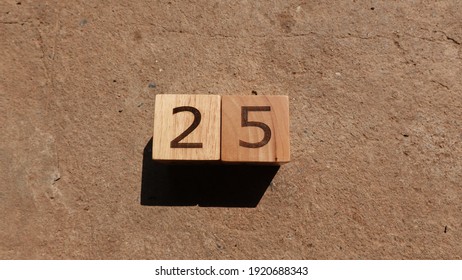Number 25 in wooden cube with concrete background. Day of Christmas and new year festival.