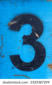 Number 3 in black paint on an old blue iron surface with rust texture and traces of dirt.