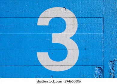 The Number 3 Painted On A Blue Wall.