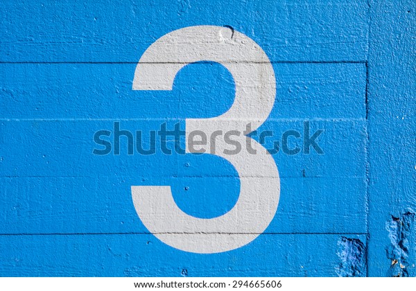 The Number 3 painted on\
a blue wall.