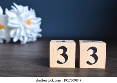 Number 33, rating, award, Empty cover design in natural concept with a number cube and peony flower on wooden table for a background.