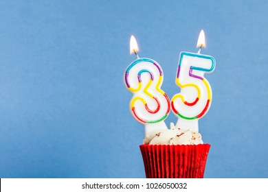 Number 35 Birthday Candle In A Cupcake Against A Blue Background