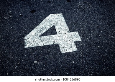 Number 4 (four) painted with white paint on asphalt, copy space 