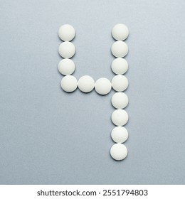 The number 4 made of white pills on a grey background.
