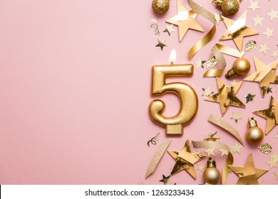 Number 5 gold celebration candle on star and glitter background