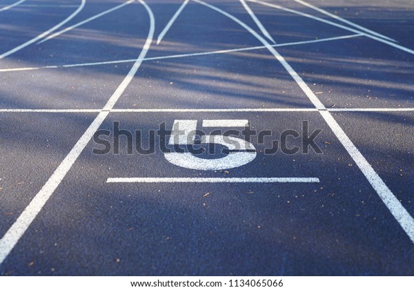 Number 5 start position of an outdoor\
stadium running track with white dividing\
lines