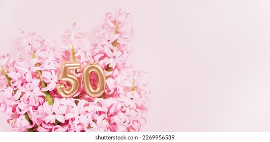 Number 50 fifty golden celebration birthday candle on Pink flowers Background. 50 years birthday. concept of celebrating birthday, anniversary, important date, holiday hyacinth bouquet. space for text - Powered by Shutterstock