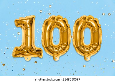 The number of the balloon made of golden foil, the number one hundred on a blue background with sequins. Birthday greeting card with inscription 100. Anniversary concept. Celebration event, template.