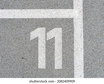 Number eleven painted on soft rubber surface. Eleventh place. Jumping hopscotch game with numbers. Safety outdoor playground