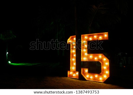 Number fifteen with lights on and clear - fifteen years - fifteen illuminated - large and clear number against dark background
