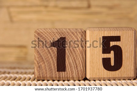 The number fifteen on a wooden cube on a beige background. Cube on a bamboo Mat.