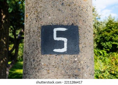 The Number Five Stencil On The Surface Of A Concrete Pillar. Numeral 5 Close-up White Text On A Black Background