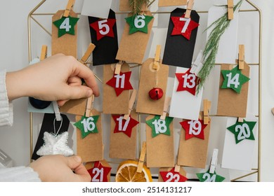 Number on craft paper notes with tasks before Christmas holidays. Female making kraft paper for handmade advent calendar Made with your own hands step by step DIY - Powered by Shutterstock