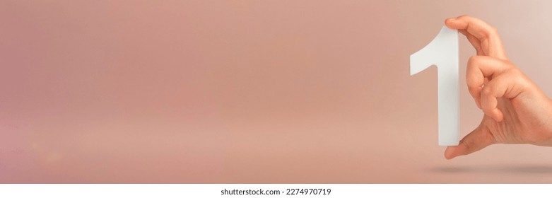 Number one in hand. A hand holds a white number one on a red background with copy space. Concept with number one. 1 percent rate, birthday, first or winner. - Shutterstock ID 2274970719