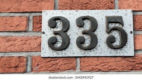 Number plate. Number 335 against a red brick wall background. Concept from a room and a wall. High resolution 150 megapixels