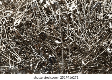 A number of stainless safety pins on white background.