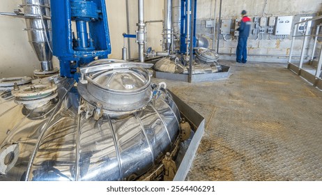 A number of steel tanks for mixing liquids timelapse hyperlapse. Stainless steel, industry. Operator near control panel - Powered by Shutterstock