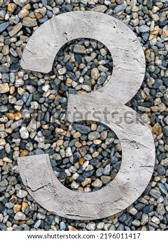 Number three with concrete texture, on stones background