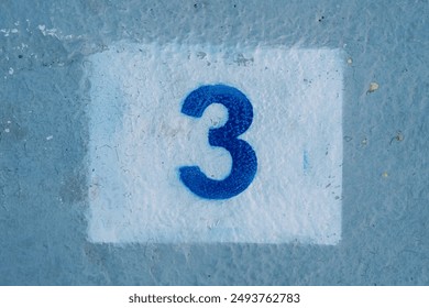 Number three drawn in a rectangle on a blue painted wall
