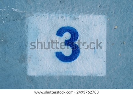 Number three drawn in a rectangle on a blue painted wall