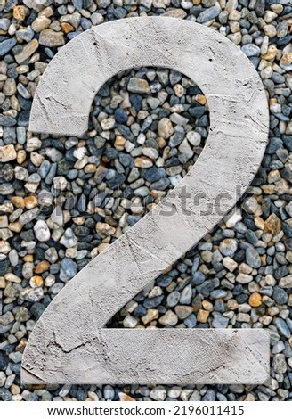 Number two with concrete texture, on stones background