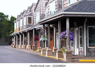 A number of two-storey wooden houses with a portico on columns and gabled roofs and walls, chipped cedar siding. On pillars portico hung baskets with colorful small flowers that create a unique. - Shutterstock ID 222608824