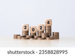 the number year 2024 in wooden cubes on top stack of coins. financial annual plan for money, Budget, tax, investment, financial, savings, and New Year Resolution concepts
