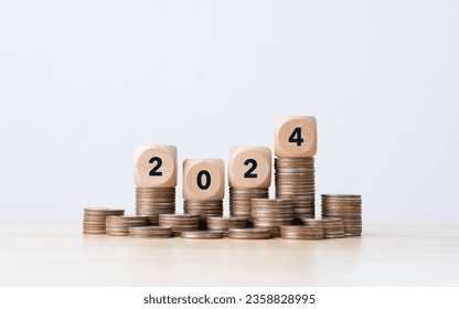 the number year 2024 in wooden cubes on top stack of coins. financial annual plan for money, Budget, tax, investment, financial, savings, and New Year Resolution concepts