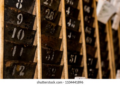 Numbered Old And Faded Time Clock Punch Card Wall Rack With Paper In The Distance