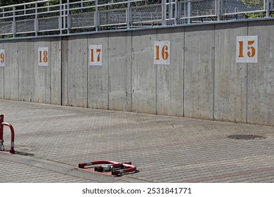 Numbered parking spots with foldable and lockable white and red tubular steel barrier posts were installed in the car park to protect the private spots for cars.
 - Powered by Shutterstock