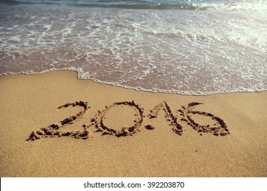 Numbers 2016 Handwritten In Golden Sand On The Beach Next To The Waterline, Representing New Summer Season