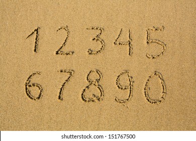 Numbers from one to ten, written on a sandy beach. 