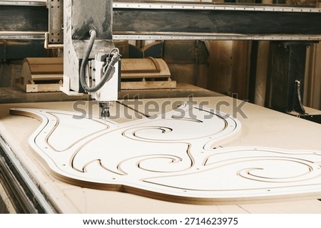 Numerically controlled woodworking machine cuts rounded complex lines on the canvas. Computer numerical control. CNC.