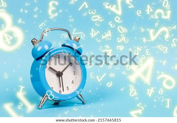 numerology, blue alarm clock on a blue\
background, surrounded by\
numbers