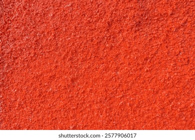 A numerous small, irregularly shaped red plastic pieces. These granulated fragments seem prepared for recycling or manufacturing purposes.