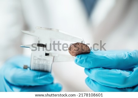 Numismatics expert in a museum research center identifying and documenting coin collection, using caliper